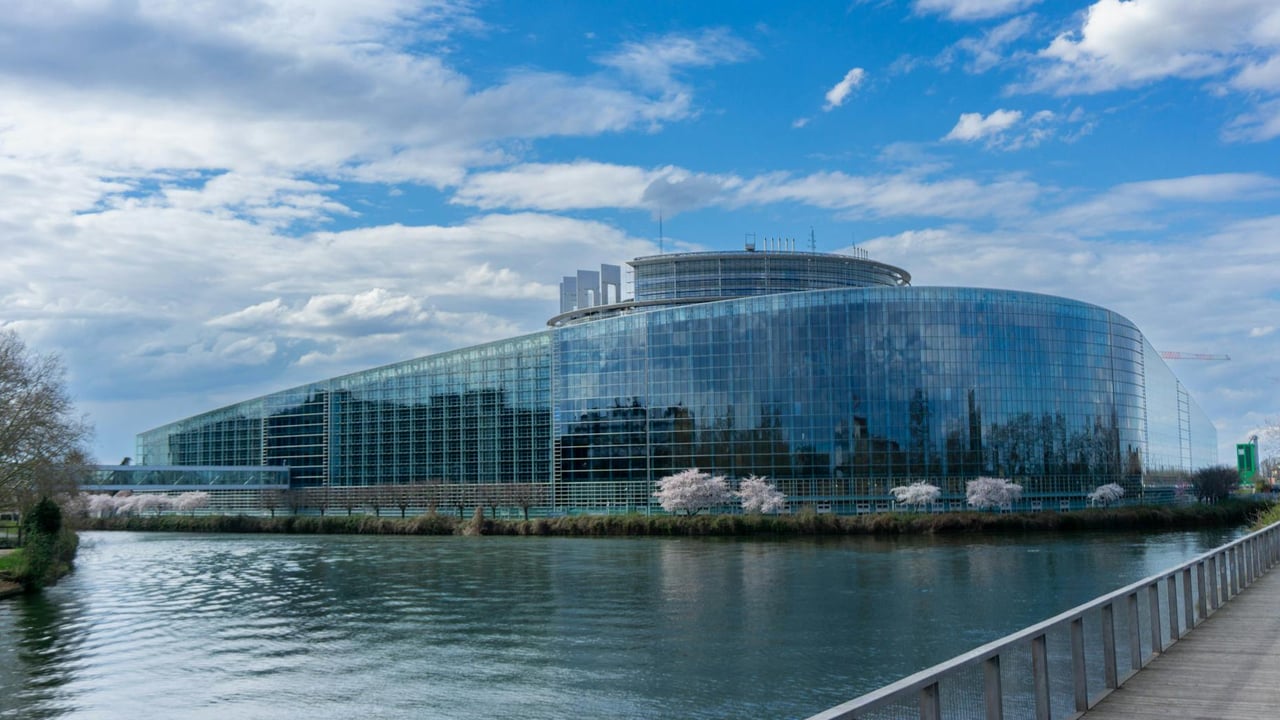 Modern architecture of the European Parliament building in Strasbourg with a reflective glass facade and river view.