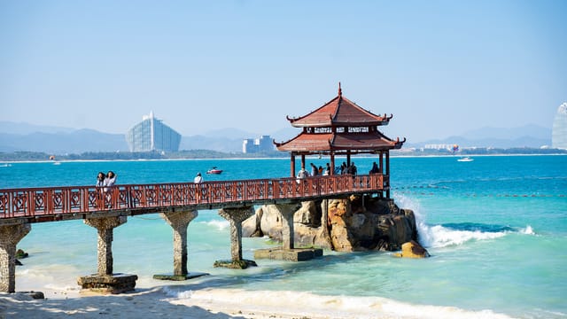 Idyllic view of a beach pier with a traditional pavilion against a clear blue sea and sky.