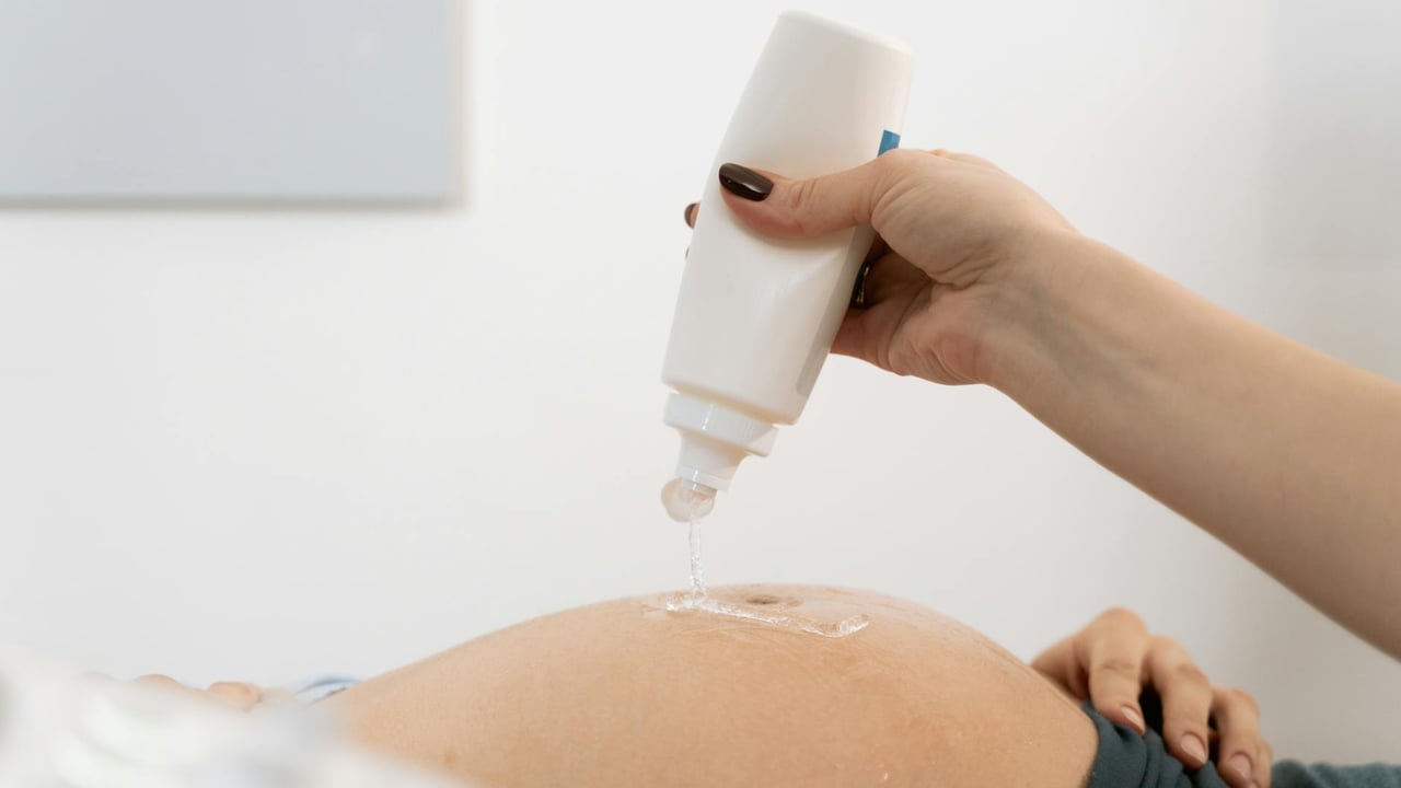 Close-up of a pregnant woman's belly with ultrasound gel being applied for a sonography session.
