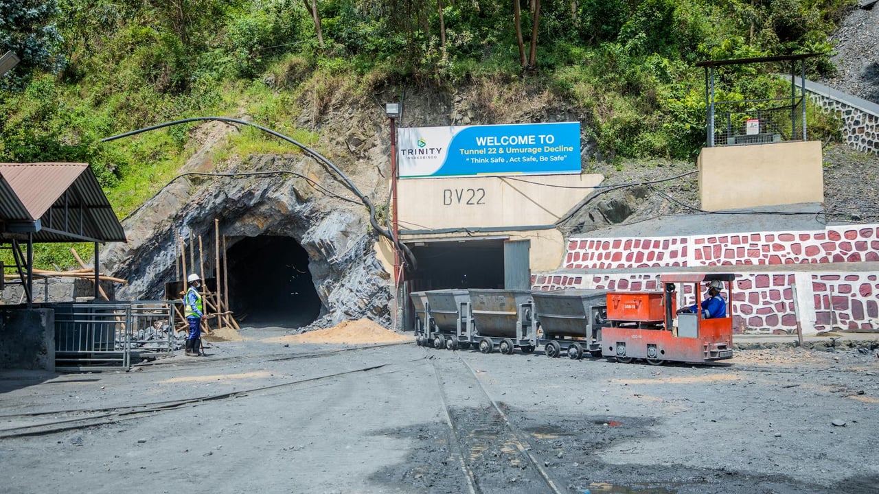 Mining entrance with tunnel BV22, rail cars, and workers in safety gear at Trinity site.