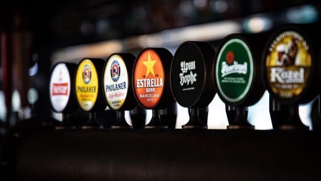 A variety of beer taps featuring distinct brand labels in a row at a bar setting.