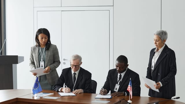 Business leaders signing a significant agreement in a conference room setting.