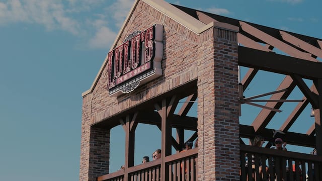 Outdoor terrace of Lu Lu's Public House with people enjoying a sunny day under a blue sky.