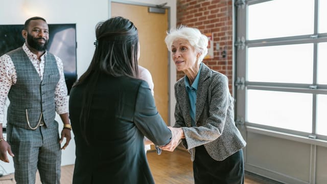 Three entrepreneurs meeting and shaking hands in a modern office setting.