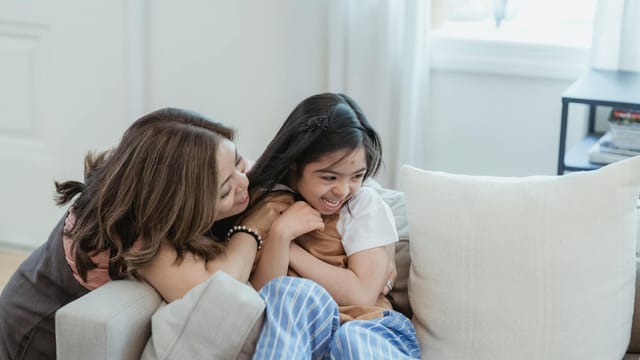 Joyful mother and daughter embracing and laughing at home.