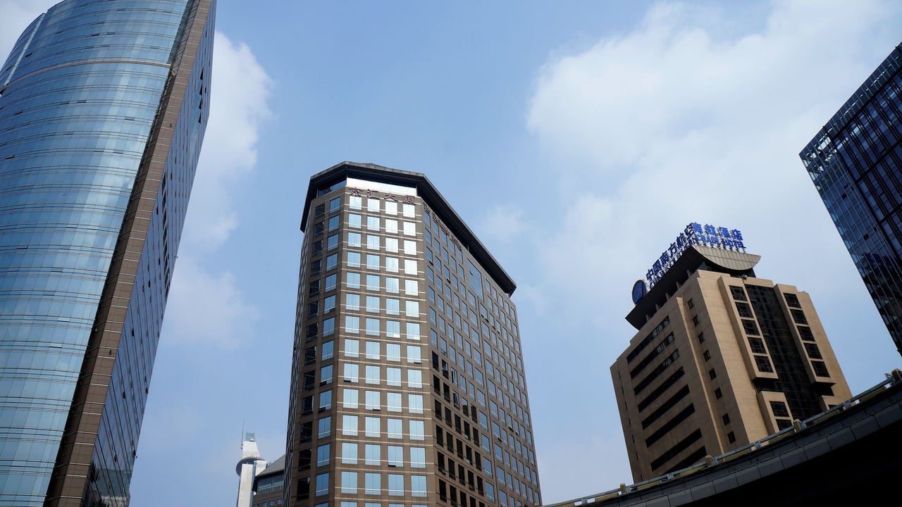 Low angle view of skyscrapers against a blue sky in a bustling cityscape.
