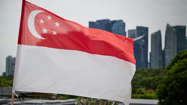 Singapore national flag waving with city skyline backdrop, symbolizing pride and modernity.