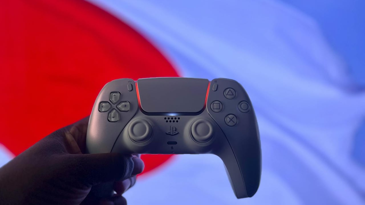 A PlayStation 5 DualSense controller is held up against a backdrop of the Japanese flag.