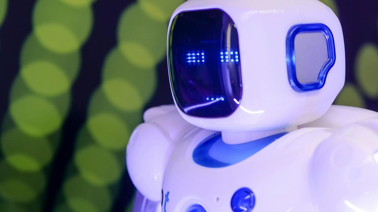 Close-up of a modern humanoid robot with glowing blue features on a green abstract background.