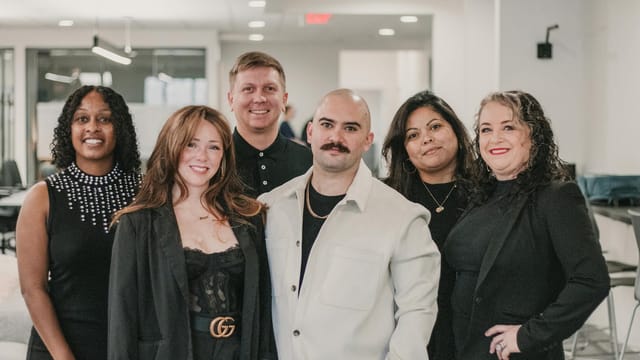 Diverse real estate professionals posing confidently in a modern office environment.