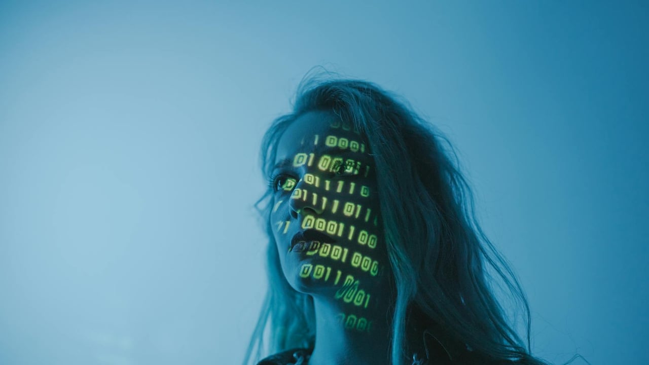 A woman with binary code lights projected on her face, symbolizing technology.
