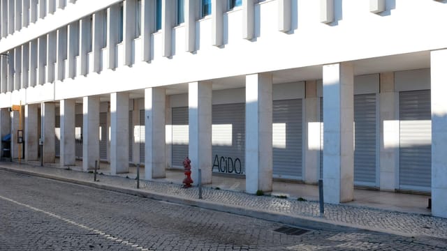 Modern street with colonnaded building and graffiti in Lisbon, Portugal.