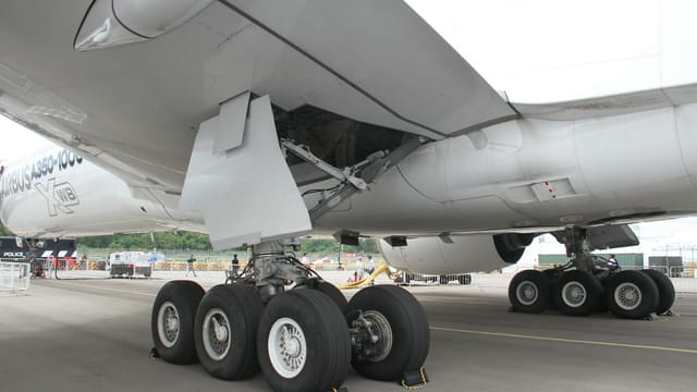 Close-up of an Airbus A350-1000's landing gear while parked on a tarmac.