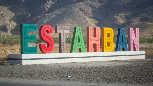Vibrant Estahban sign with mountainous backdrop in Fars Province, Iran.