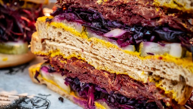 Close-up of a delicious salted beef sandwich with mustard and fresh vegetables.