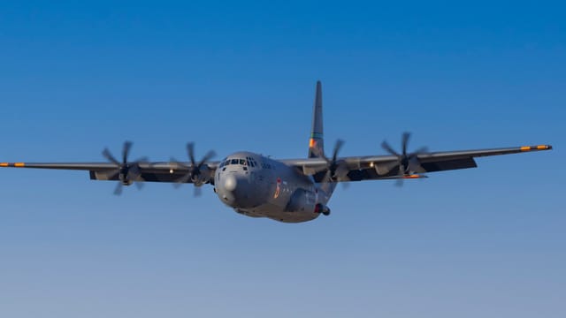 Military aircraft flying with a clear blue sky backdrop, showcasing strength and precision.