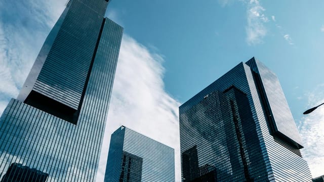 Low-angle view of modern skyscrapers reaching into a clear blue sky, capturing urban architecture.