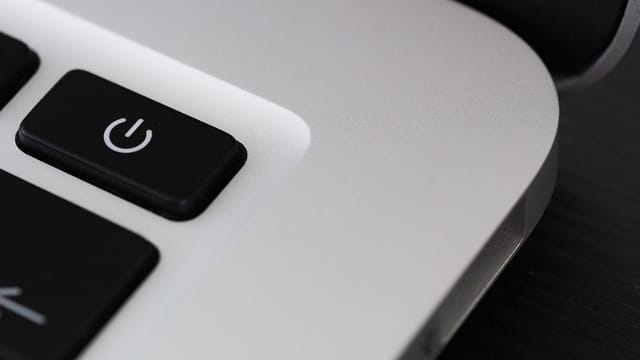 Detailed view of a power button on a sleek laptop, emphasizing technology design.