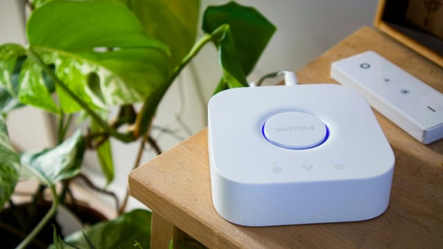 Philips smart hub beside a leafy plant in a stylish indoor setting, showcasing modern home automation.