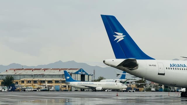 Airplanes of Ariana Afghan Airlines parked at Kabul Airport with a mountain backdrop.