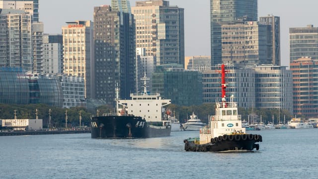 Explore the bustling waterfront of Shanghai with boats and towering modern skyscrapers.