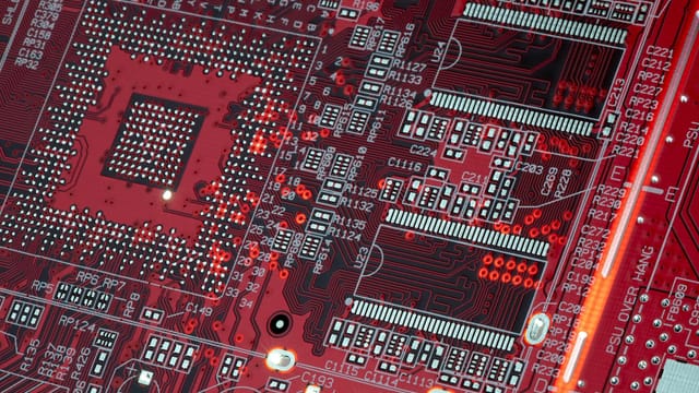 Detailed shot of a red motherboard showcasing electronic components and circuits.