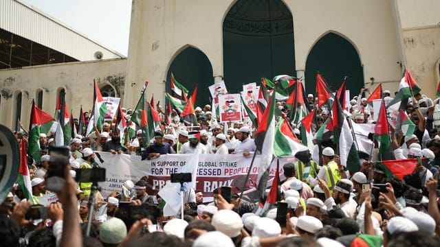 Crowd gathers in Dhaka for a pro-Palestinian demonstration waving flags and banners.