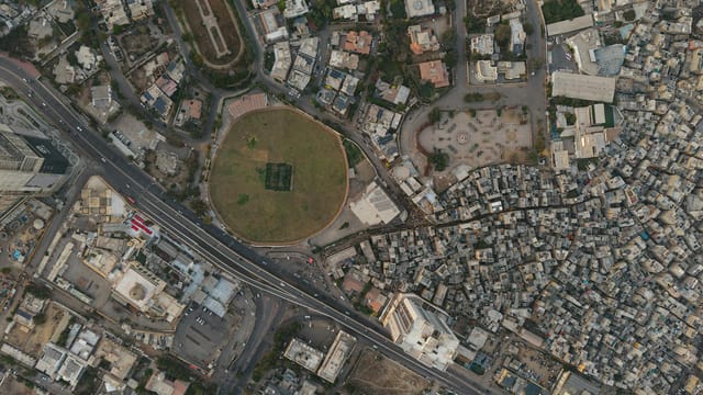 A detailed aerial shot of Karachi showing dense settlements and a distinct circular park, highlighting urban development.