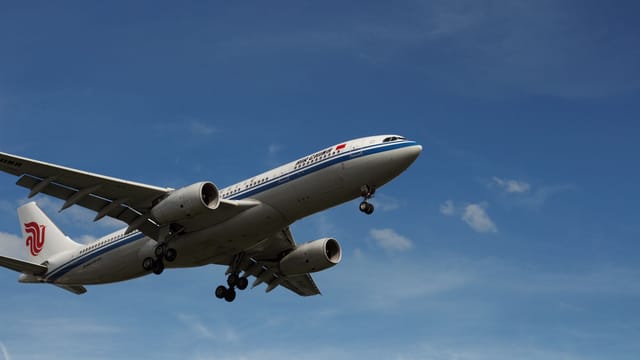 A commercial airplane in flight against a clear blue sky, showcasing modern air travel.