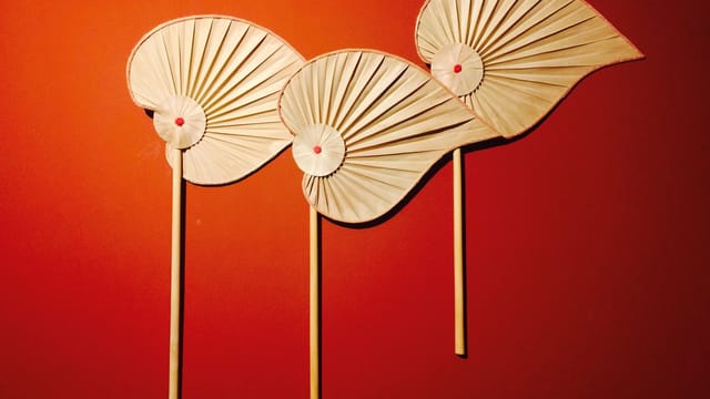 Decorative wooden fan display on a vibrant red wall, offering ample copy space.