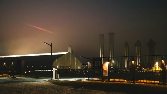 Dramatic night view of SpaceX facility with fog and lights in Brownsville, Texas.