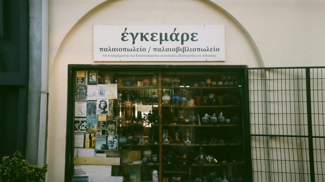 Explore a vintage storefront in Ayvalık, Turkey featuring ceramics and books.