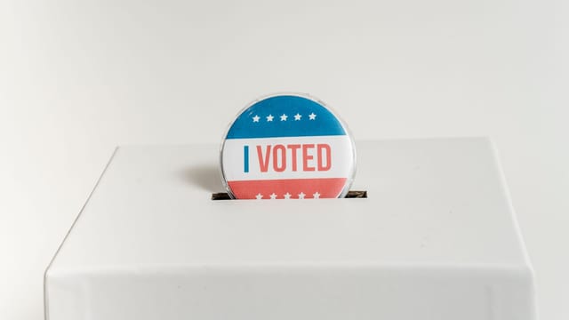 Close-up of an I Voted badge on a ballot box, symbolizing voting in the USA elections.