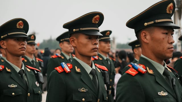 Close-up of military personnel in green uniforms and hats during a parade.