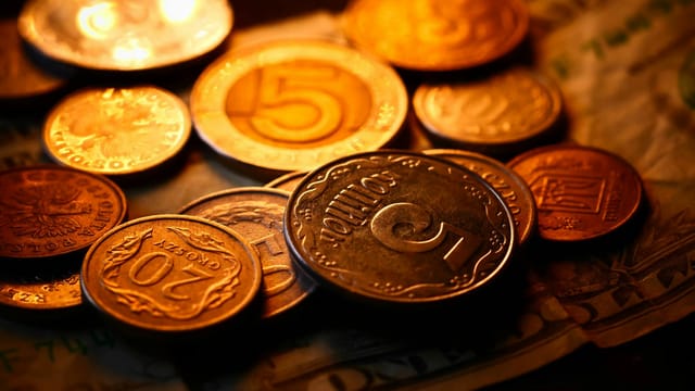 A detailed close-up of various international coins and banknotes with warm lighting, ideal for finance themes.