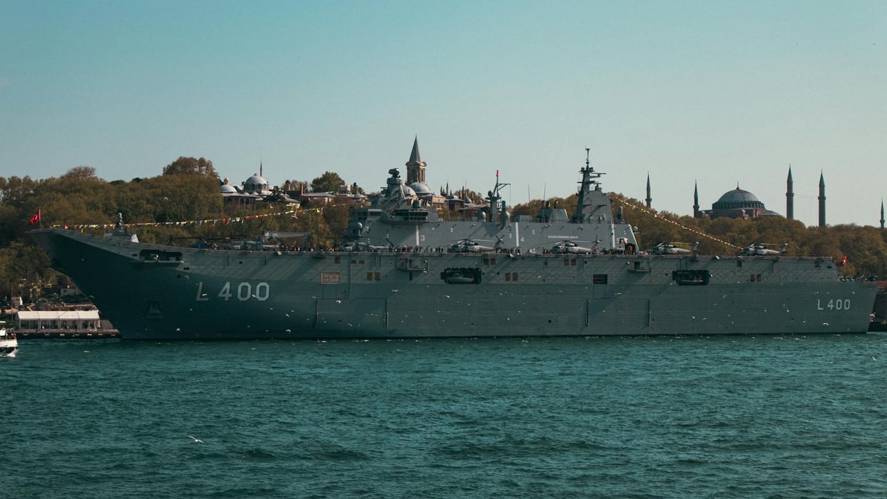 A formidable battleship navigating Istanbul's scenic waterfront under a clear sky.