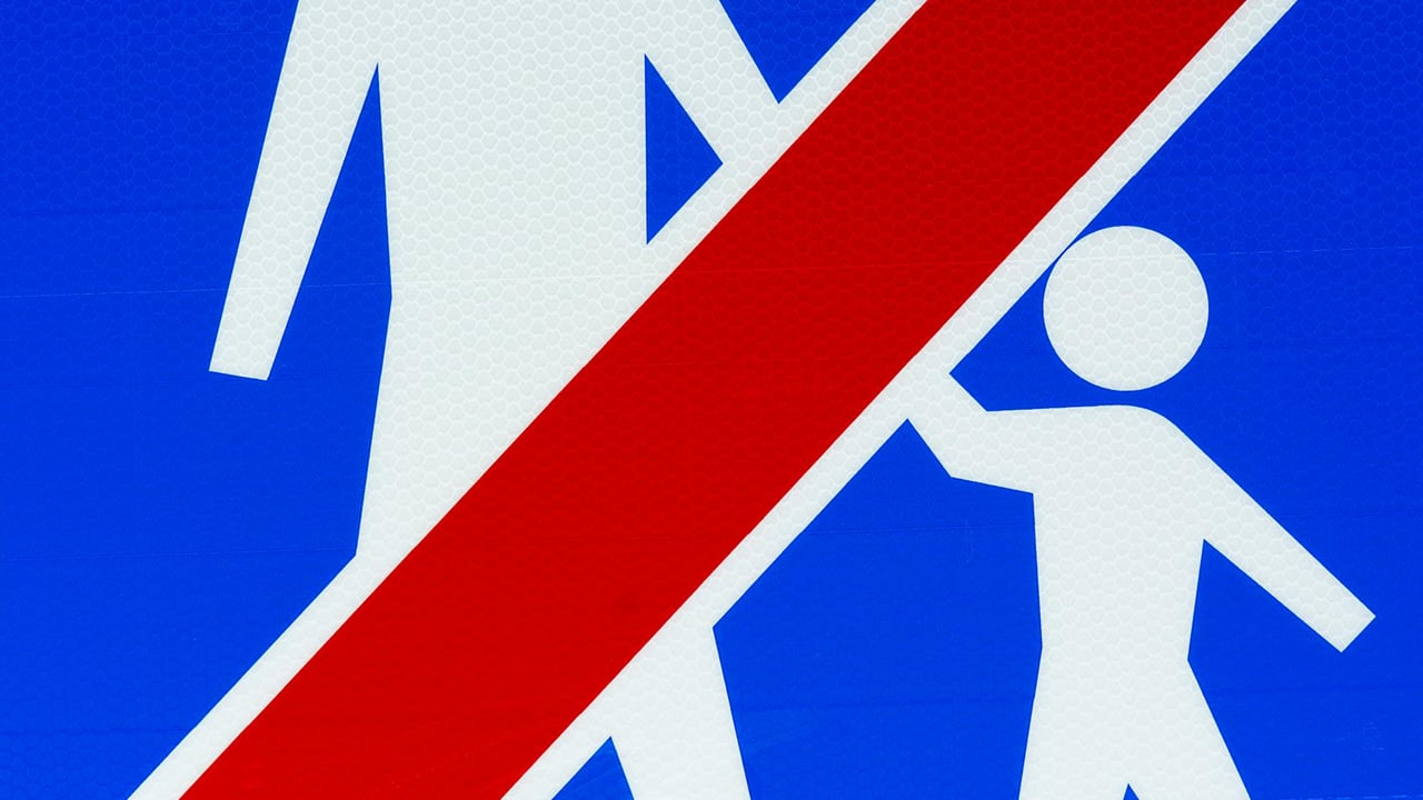 Close-up of a pedestrian prohibition sign with graphic elements on a blue background.