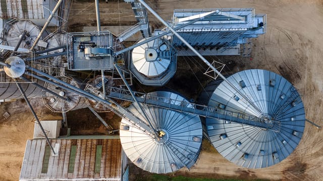 Drone shot of metal grain silos in Utica, MN, showcasing industrial agriculture.