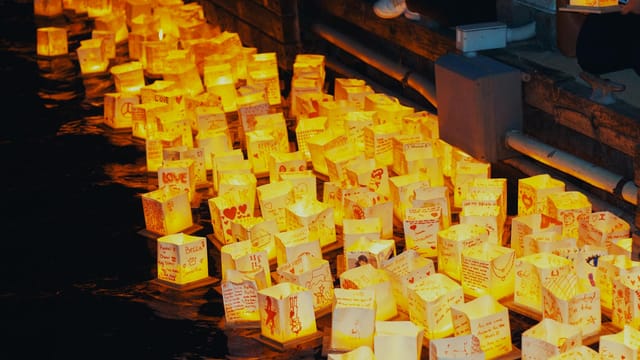 Illuminated lanterns floating on water during the Detroit Water Lantern Festival at night.