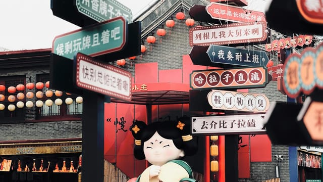 Vibrant Chinese market scene featuring colorful signs and festive lanterns during the day.