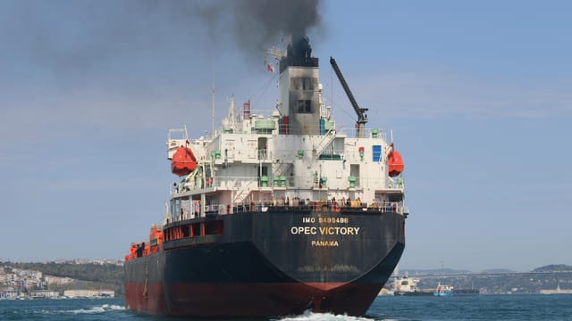 Oil tanker OPEC Victory sailing on the Bosporus under clear skies, emitting smoke.