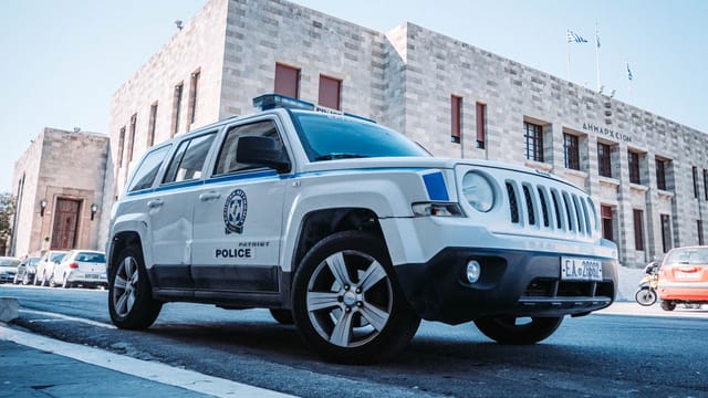 A Greek police car parked on a street in Rodos, Greece, showcasing local architecture.