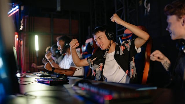 Excited gamers celebrating a win in a competitive gaming tournament with headphones.