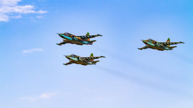 Sukhoi Su-25 aircrafts flying in perfect formation against a clear blue sky.