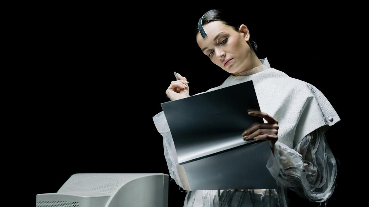A female scientist with futuristic attire reviews notes in an advanced lab setting.
