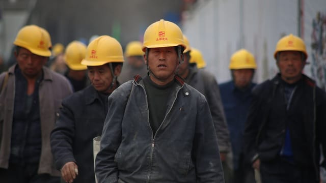 Construction workers in hard hats walking at a site, highlighting teamwork and safety.