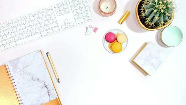 Minimalist office desk setup with cactus, keyboard, and colorful macarons for a modern aesthetic.