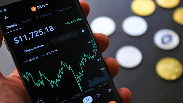 Close-up of Bitcoin trading app on smartphone showing market trends and digital coins.