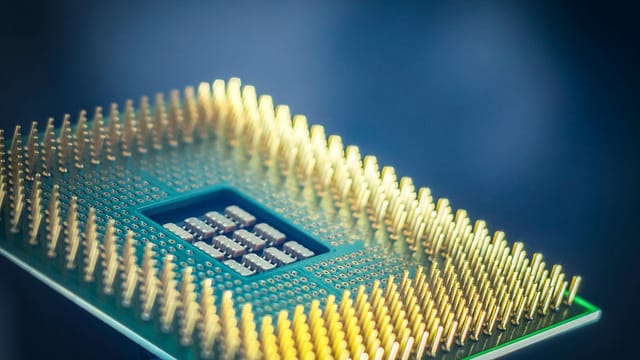 High-resolution macro shot of a computer CPU chip with gold pins against a blue background.