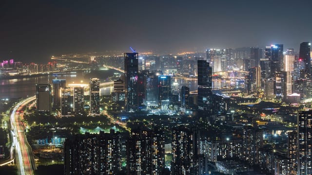 Stunning urban skyline at night with illuminated skyscrapers and bustling city lights.